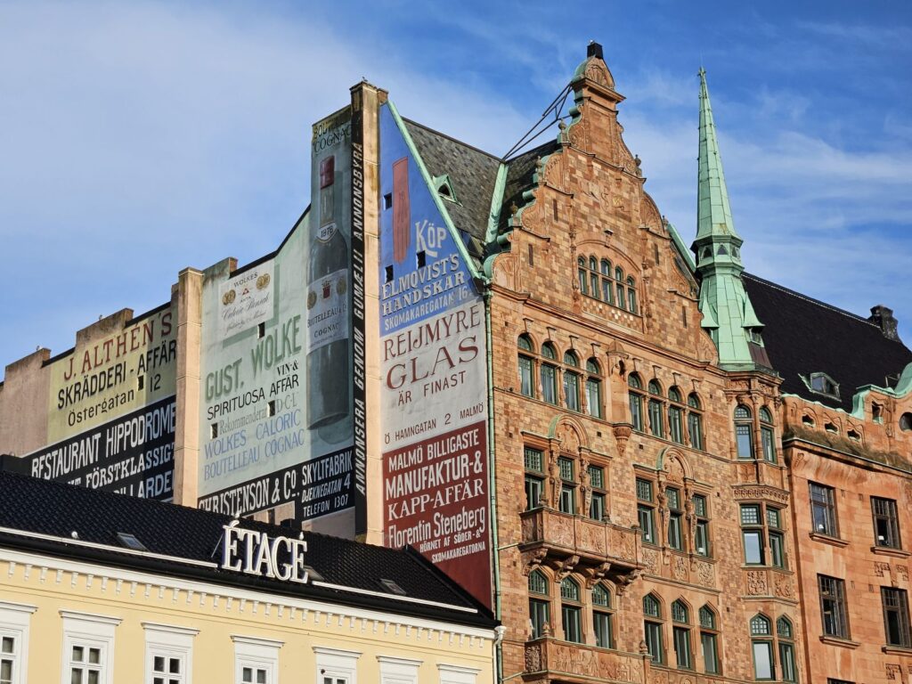 Die Fassade der Löwenapotheke, begleitet von Werbebotschaften, Malmö